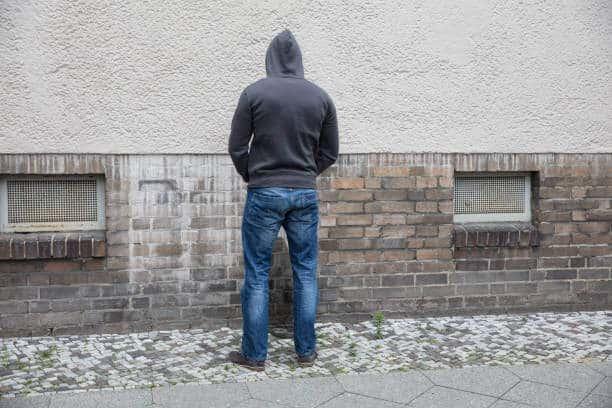 Rear View Of A Man In Hood Peeing