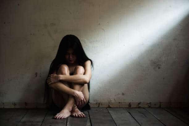 Depressed woman sitting on bare floor