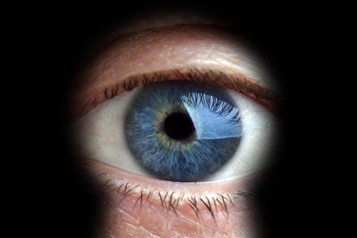 Mans eye looking through a blured keyhole