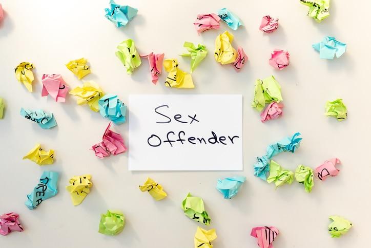 Word sex offender handwritten on a white card with a crumpled paper and white isolated background