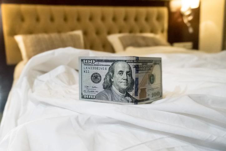 bed and money to symbolize the cost of sex. Paid love the prostitute. Payment for the services of prostitutes. A tip for the staff. buck 100 on the bed. monetary gratitude